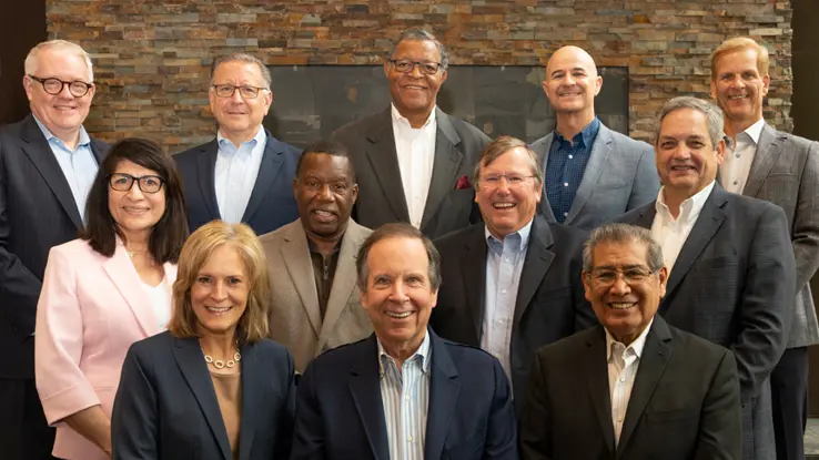 A group of men and women in business attire smiling at the camera 