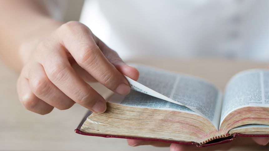 Person turning the pages of a Bible