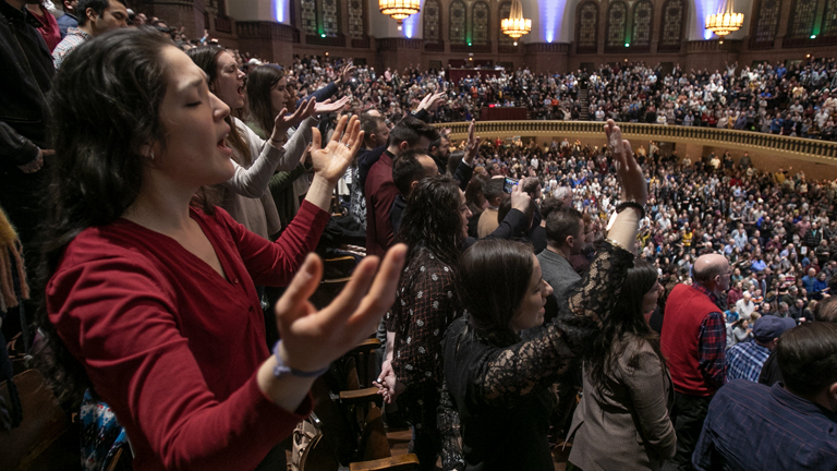 A group of people singing and worshipping in Moody Church