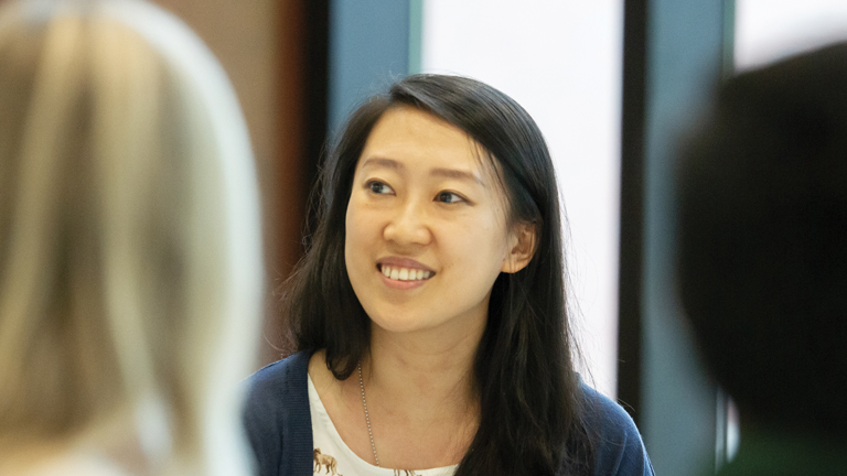 A woman smiling in a blue sweater.