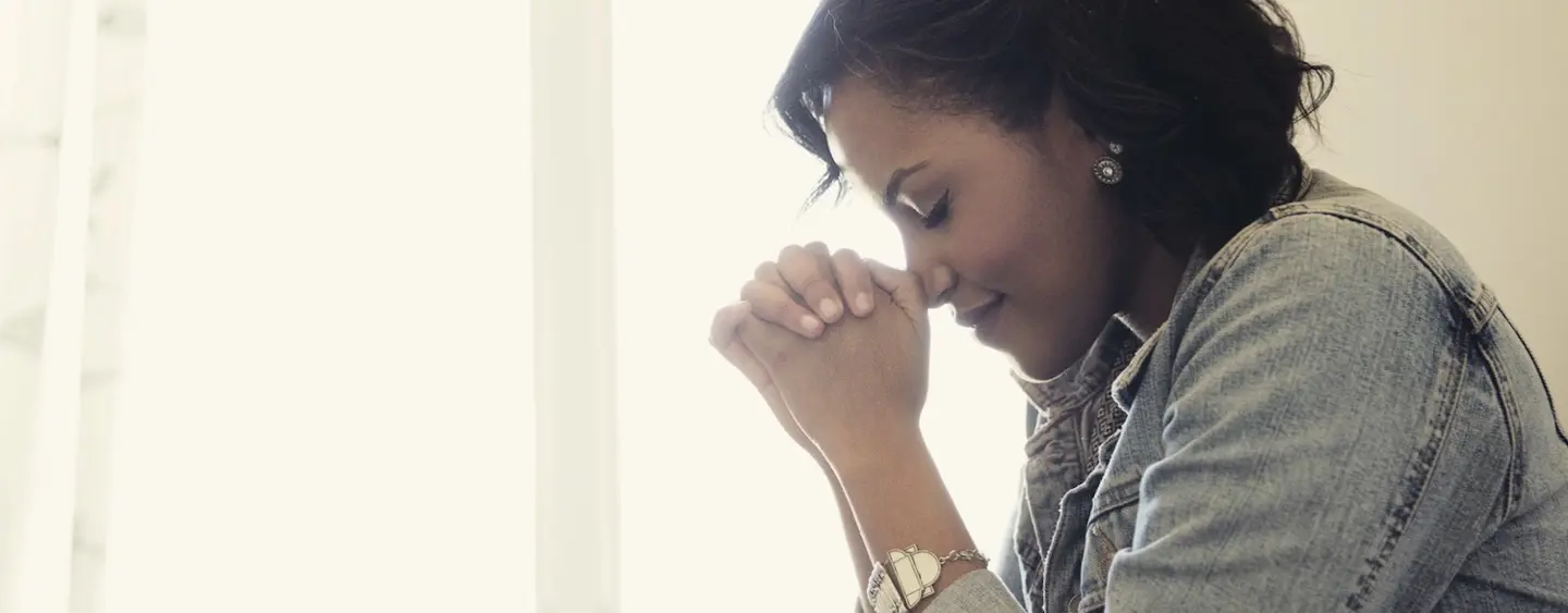 Woman praying with her hands folded and head bowed